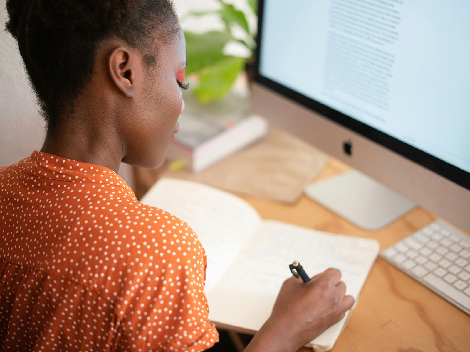 Warren UC - Private International College Consulting - Strategies for Tackling the College Essay blog post - Woman writing in notebook sitting in front of a computer - Pexels RF._.studio