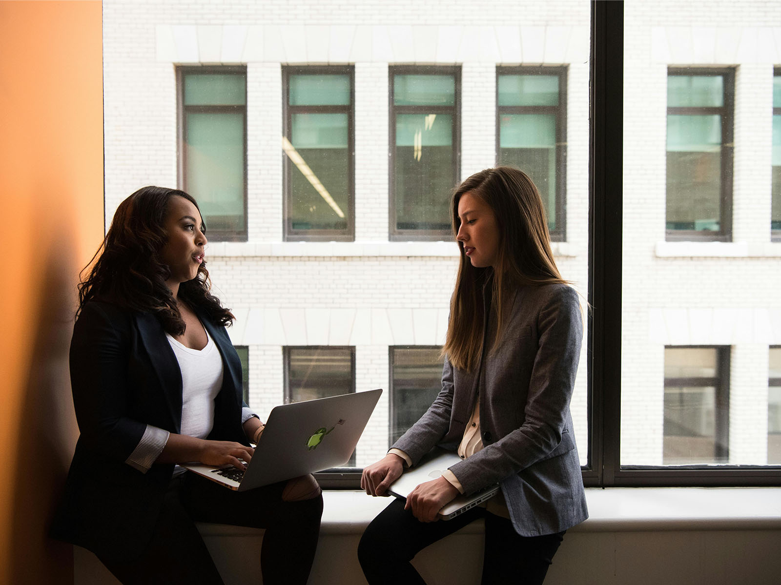 Warren UC - Private International College Consulting - Top Business Schools blog - Two women with laptops talking by windows - Pexels Christina Morillo